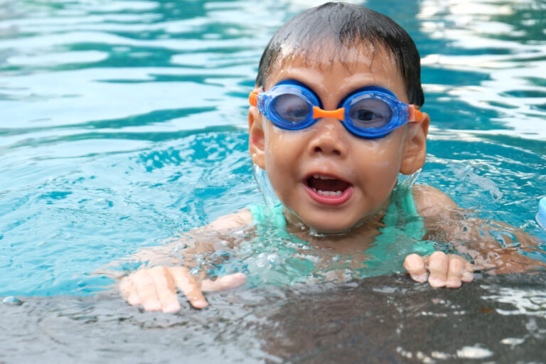 asian cute boy  splashing on summer pool